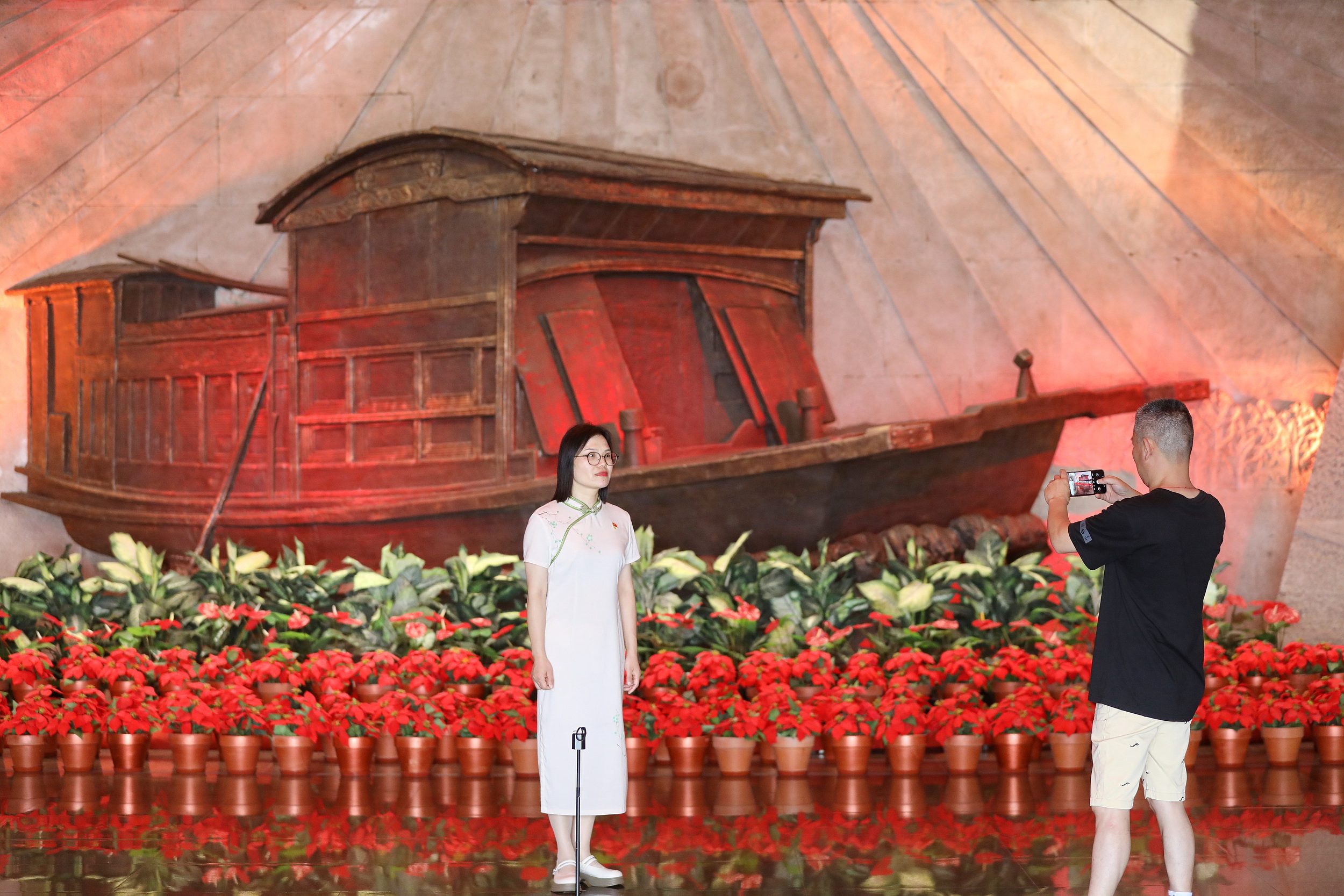 2025年6月24日，浙江嘉興，游客在南湖革命紀(jì)念館與紅船雕塑合影。（圖片來源：視覺中國）