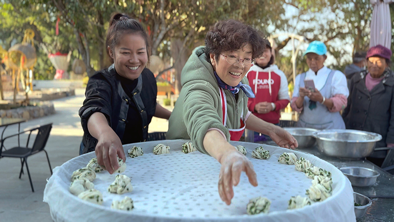 【2】旅居者趙發(fā)英（圖左二）教曼海村村民做花卷。陶思源-攝